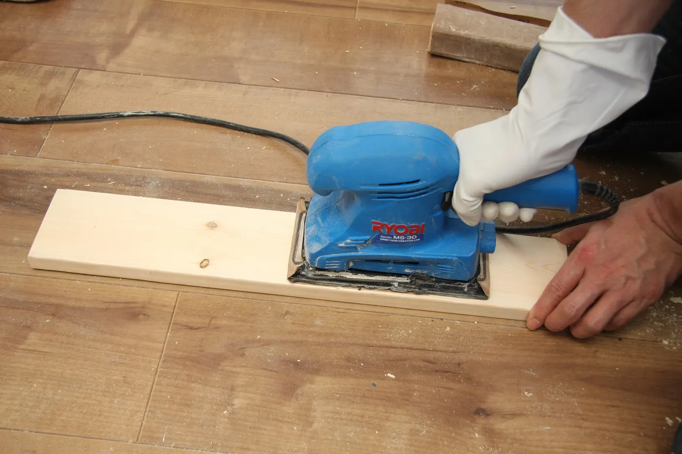 A board of wood trim being sanded smooth