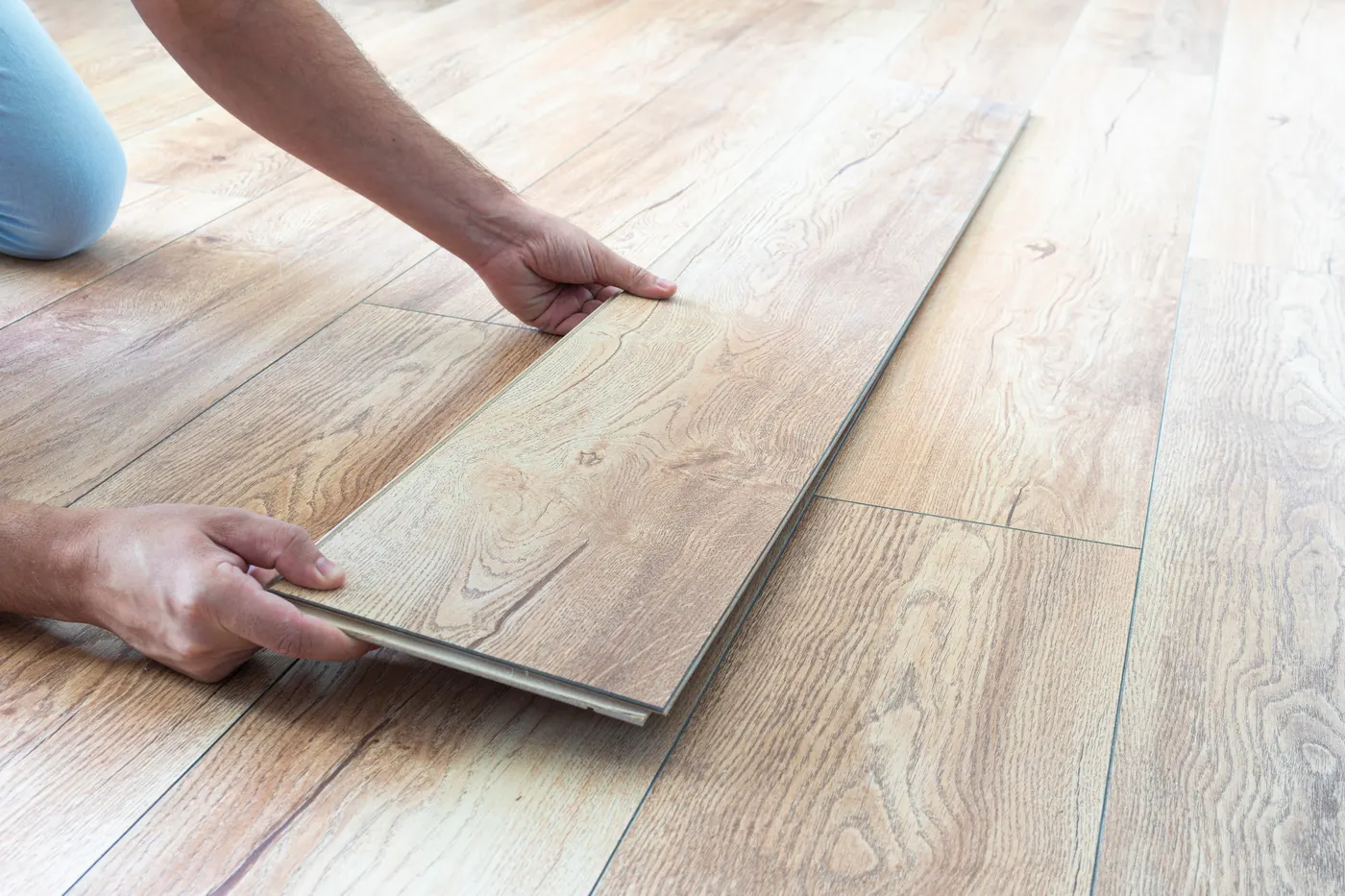 A flooring installer laying a new wood-look plank floor