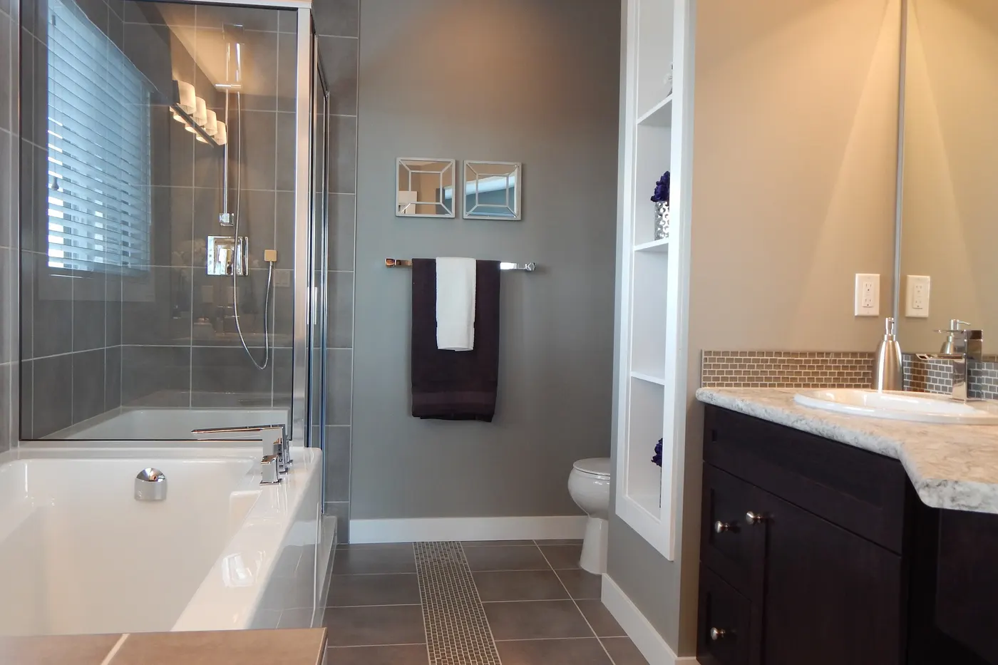 A remodeled bathroom with a tiled tub surround and a dark wood vanity