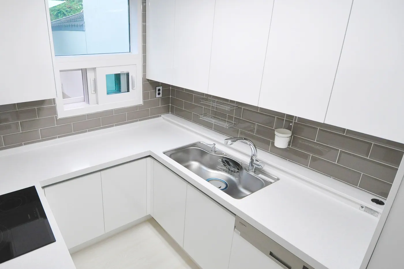 A white kitchen with a gray tiled backsplash